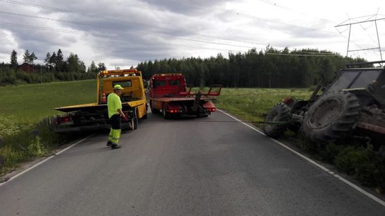 kaksi hinauspalvelun autoa ja yksi työntekijä hinaamassa traktoria ojasta Nokian lähistöllä Pirkanmaalla